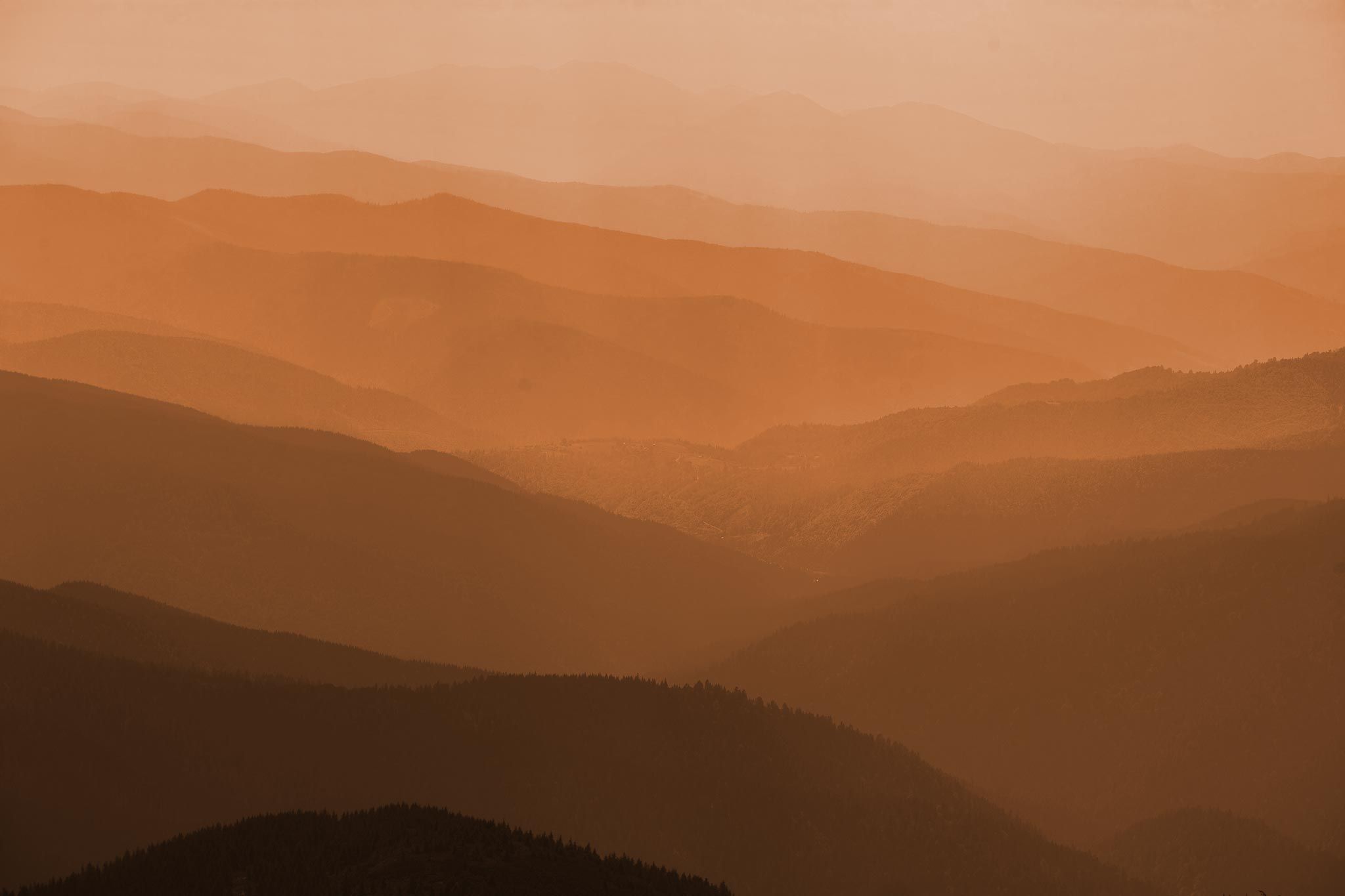 Rolling mountains that fade into the distance in a hazy shot that looks like there is smoke from a fire